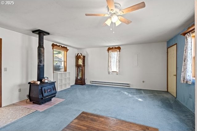 387 E Linden Way, Heppner, OR 97836 - unfurnished living room featuring a baseboard heating unit, a wood stove, carpet floors, and plenty of natural light