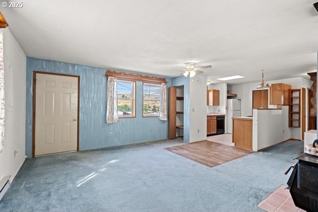 387 E Linden Way, Heppner, OR 97836 - unfurnished living room featuring a ceiling fan, light carpet, a wood stove, and a baseboard radiator
