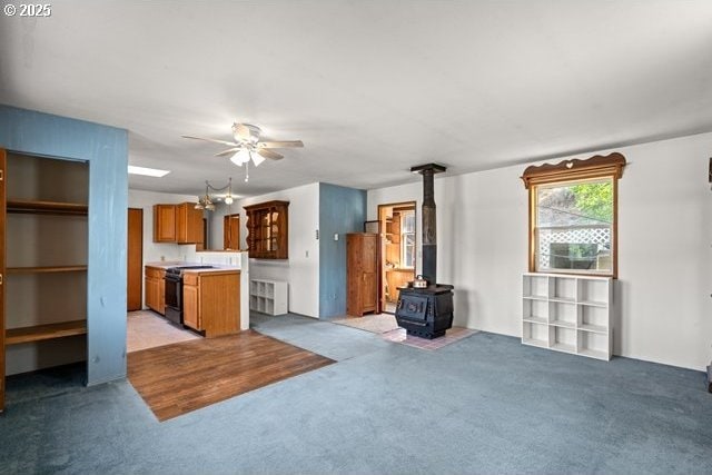 387 E Linden Way, Heppner, OR 97836 - unfurnished living room with light carpet, a wood stove, and a ceiling fan