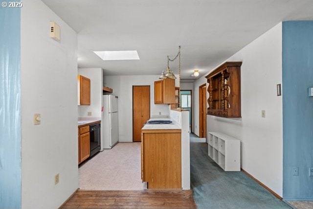 387 E Linden Way, Heppner, OR 97836 - kitchen with black dishwasher, a skylight, freestanding refrigerator, light countertops, and brown cabinetry