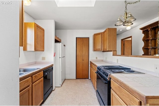 387 E Linden Way, Heppner, OR 97836 - kitchen featuring black appliances, a chandelier, brown cabinetry, light flooring, and hanging light fixtures