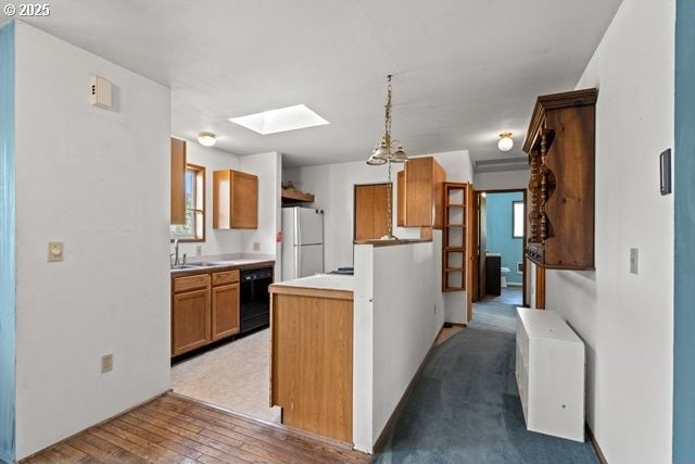 387 E Linden Way, Heppner, OR 97836 - kitchen with freestanding refrigerator, a skylight, black dishwasher, light countertops, and brown cabinetry