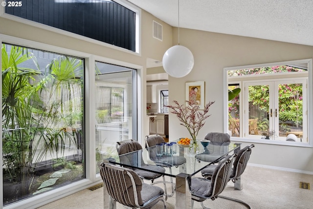 carpeted dining space featuring plenty of natural light, vaulted ceiling, and visible vents