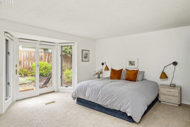 bedroom featuring carpet floors, access to outside, visible vents, and a textured ceiling