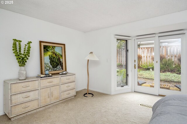 bedroom featuring a textured ceiling, access to exterior, light colored carpet, and visible vents
