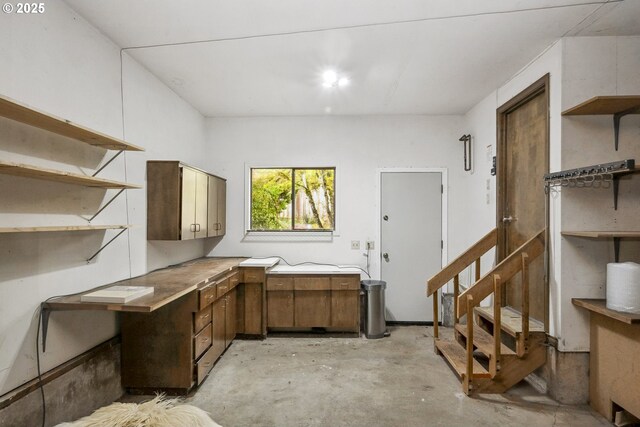 interior space with light countertops, unfinished concrete flooring, open shelves, and brown cabinets