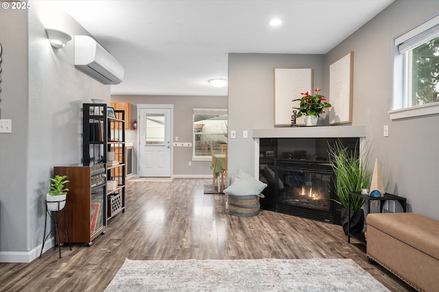 living room featuring wood-type flooring and a wall unit AC