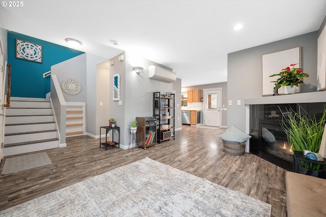 living room with hardwood / wood-style flooring, a tiled fireplace, and a wall mounted air conditioner