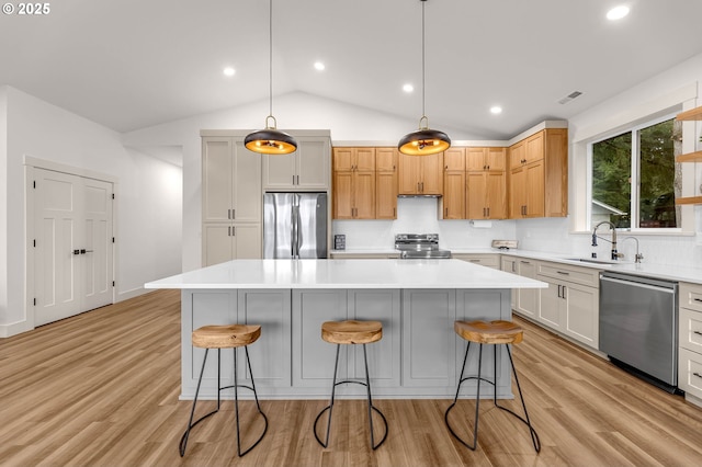 kitchen featuring hanging light fixtures, a kitchen island, appliances with stainless steel finishes, and light countertops