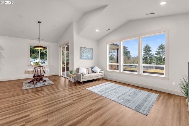 unfurnished room with lofted ceiling, a wealth of natural light, and light wood-style flooring