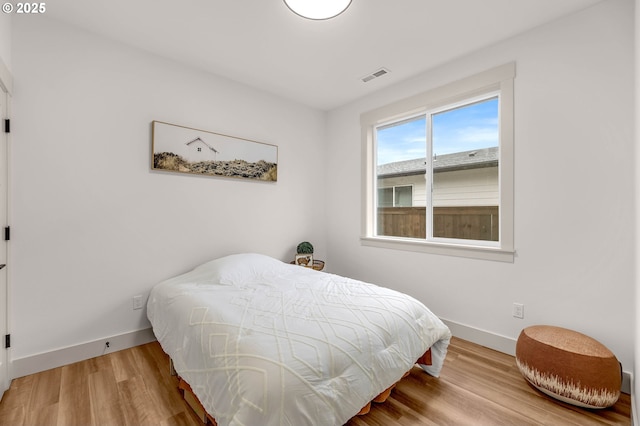 bedroom featuring baseboards, visible vents, and wood finished floors