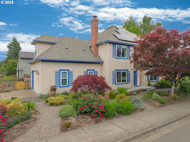 view of front of property with a chimney, a shingled roof, solar panels, and fence