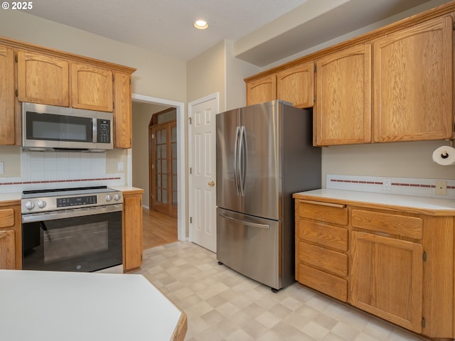 kitchen featuring appliances with stainless steel finishes, light floors, light countertops, decorative backsplash, and recessed lighting