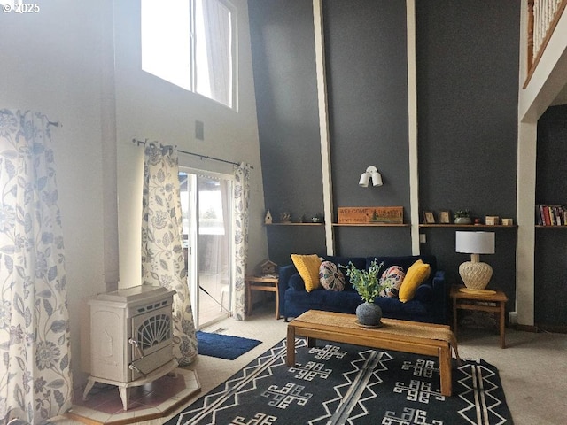 carpeted living room featuring a high ceiling, a wood stove, and a wealth of natural light