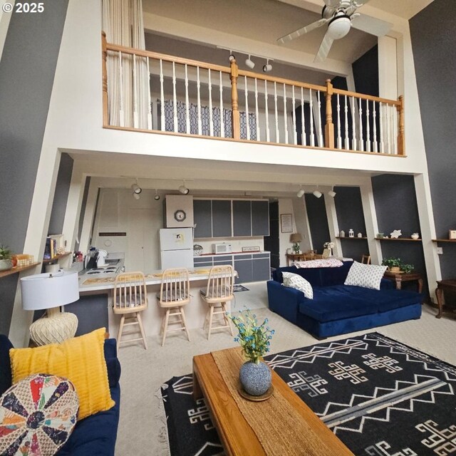 carpeted living room with a towering ceiling and ceiling fan