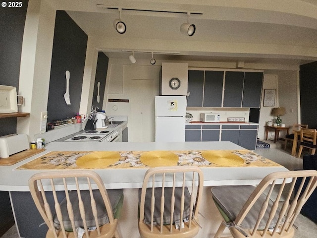 kitchen featuring white refrigerator, kitchen peninsula, sink, and stove