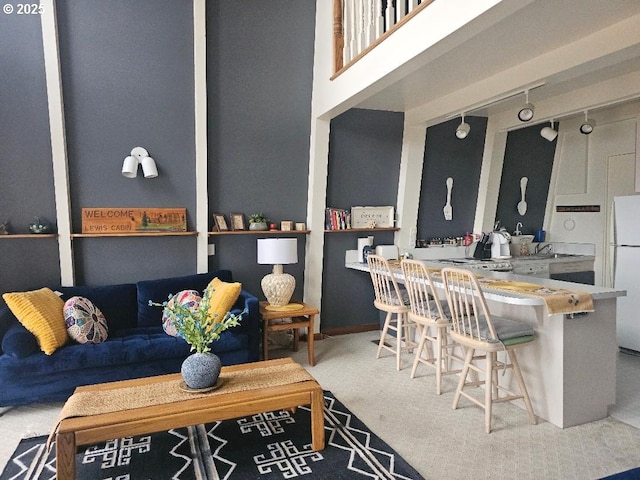 carpeted living room featuring track lighting and a high ceiling