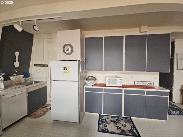 kitchen with rail lighting, sink, and white appliances