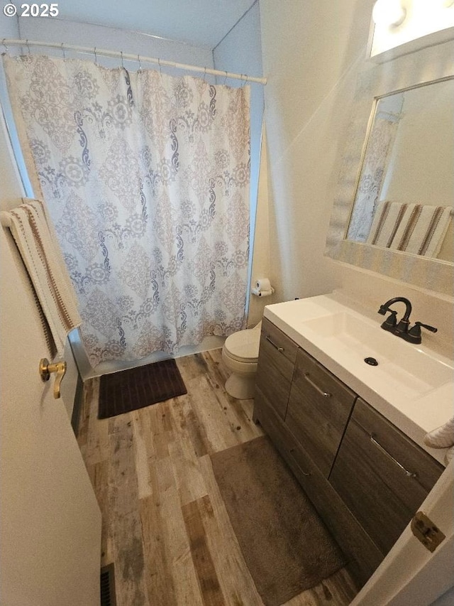 bathroom featuring vanity, wood-type flooring, a shower with shower curtain, and toilet