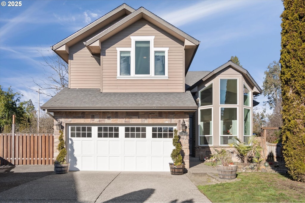 view of front facade featuring driveway, a garage, a shingled roof, stone siding, and fence