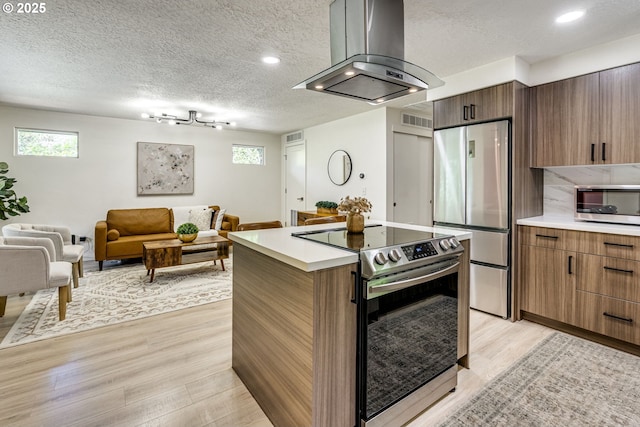 3711 N Alaska Pl, Portland, OR 97217 - kitchen featuring appliances with stainless steel finishes, island exhaust hood, light wood-type flooring, light countertops, and a textured ceiling