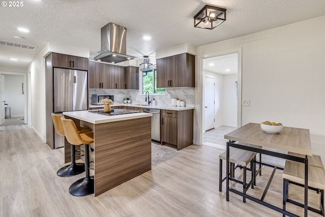 3711 N Alaska Pl, Portland, OR 97217 - kitchen featuring stainless steel appliances, island exhaust hood, a center island, a breakfast bar, and light wood-type flooring