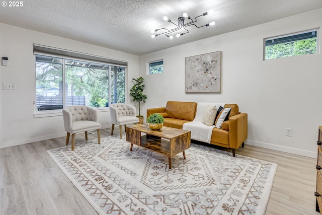 3711 N Alaska Pl, Portland, OR 97217 - living room featuring a chandelier, plenty of natural light, light wood-style floors, and a textured ceiling
