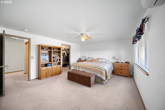 bedroom with a wall mounted air conditioner, carpet, a spacious closet, ceiling fan, and a closet