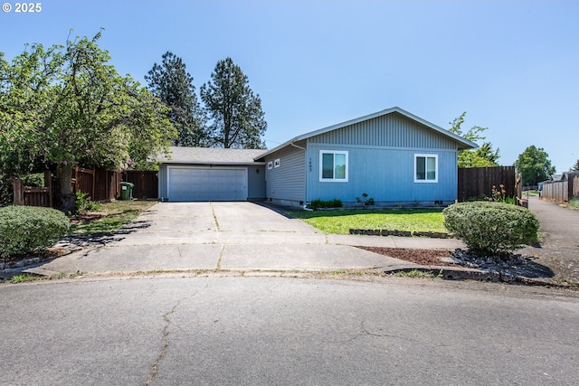 single story home featuring concrete driveway, fence, and an attached garage
