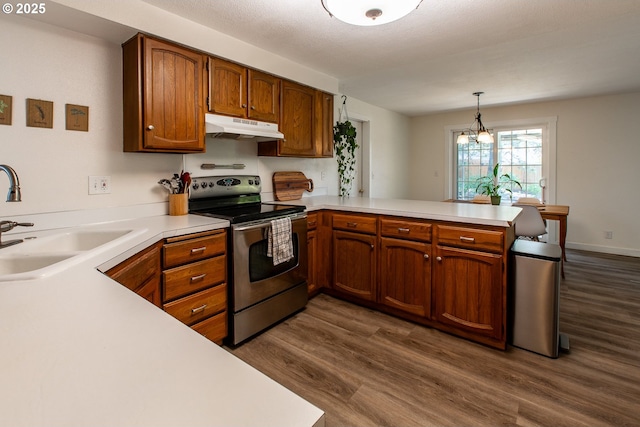 kitchen featuring stainless steel range with electric stovetop, under cabinet range hood, a peninsula, a sink, and light countertops