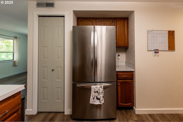 kitchen with freestanding refrigerator, dark wood finished floors, light countertops, baseboards, and brown cabinets