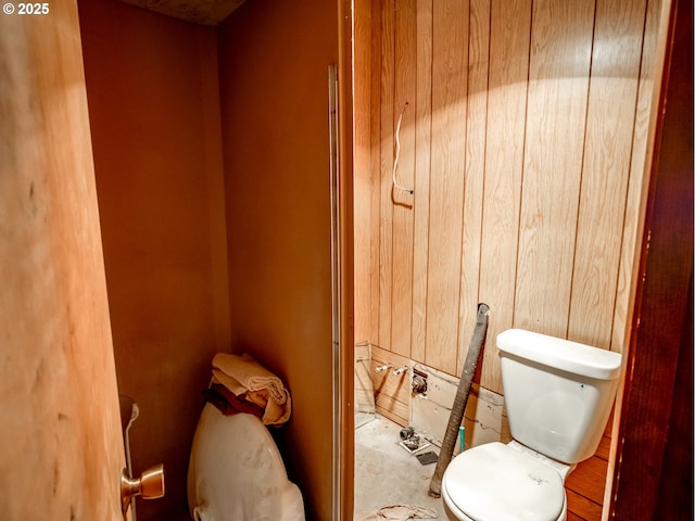 bathroom with wood walls and toilet