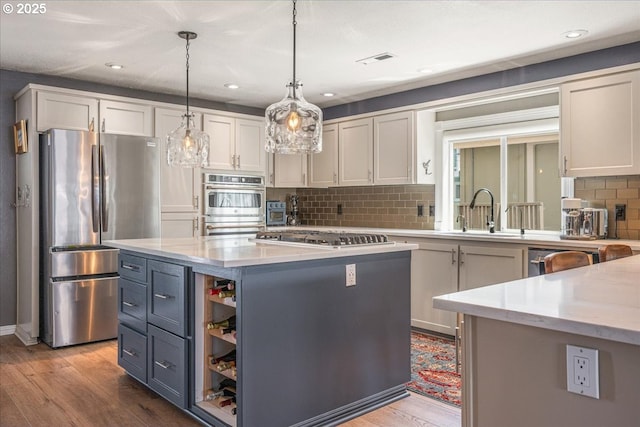 460 N Tomahawk Island Dr, Portland, OR 97217 - kitchen with appliances with stainless steel finishes, a kitchen island, light wood-type flooring, decorative backsplash, and recessed lighting