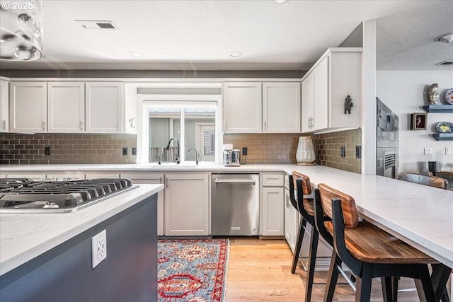 460 N Tomahawk Island Dr, Portland, OR 97217 - kitchen with stainless steel appliances, light wood-style flooring, light stone countertops, backsplash, and recessed lighting