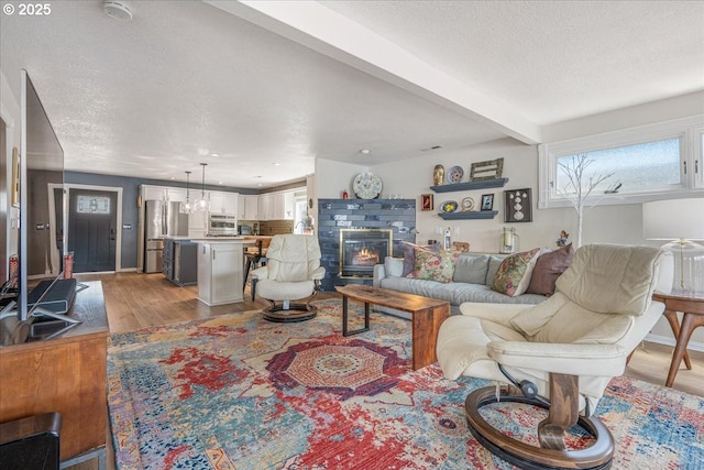 460 N Tomahawk Island Dr, Portland, OR 97217 - living room with light wood-type flooring, a glass covered fireplace, a textured ceiling, and beamed ceiling