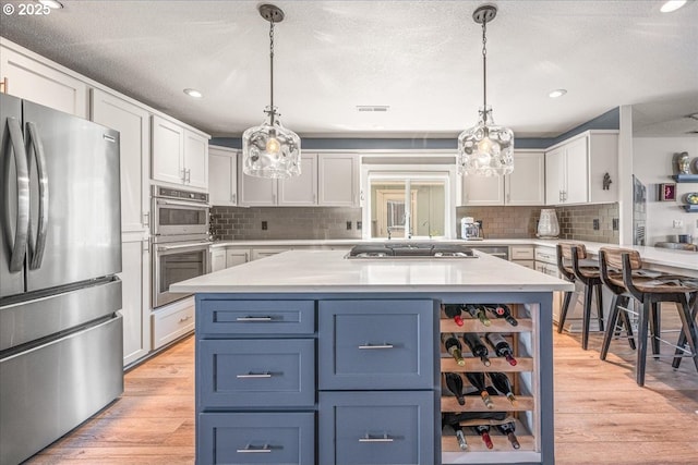 460 N Tomahawk Island Dr, Portland, OR 97217 - kitchen with stainless steel appliances, light wood-style flooring, backsplash, white cabinetry, and recessed lighting
