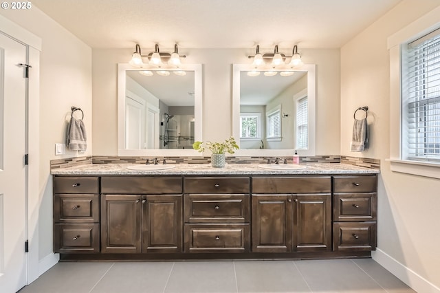 bathroom featuring plenty of natural light, baseboards, and double vanity