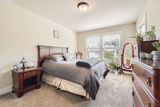 bedroom featuring light carpet, baseboards, and a textured ceiling
