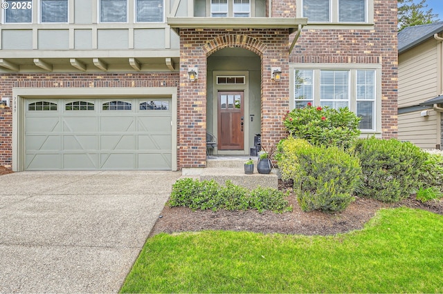 view of exterior entry with brick siding, a garage, and concrete driveway