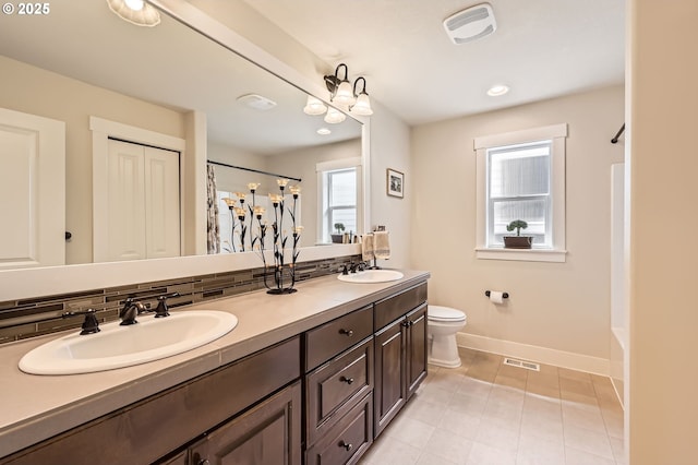 full bath featuring baseboards, a shower with curtain, double vanity, tile patterned flooring, and toilet