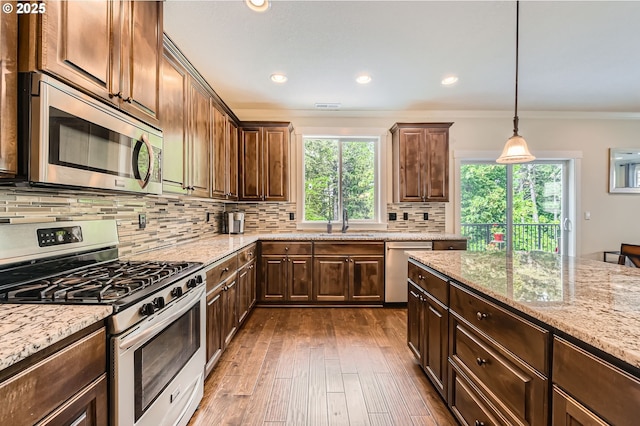 kitchen with stainless steel appliances, ornamental molding, decorative backsplash, light stone counters, and recessed lighting
