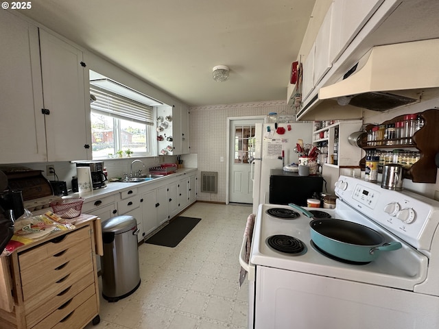 kitchen with white appliances, light floors, under cabinet range hood, and plenty of natural light