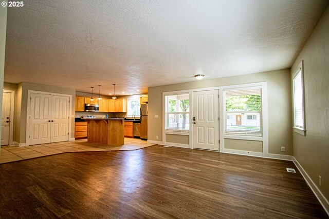 1072 53rd St, Springfield, OR 97478 - kitchen featuring stainless steel appliances, wood finished floors, a textured ceiling, baseboards, and a breakfast bar area