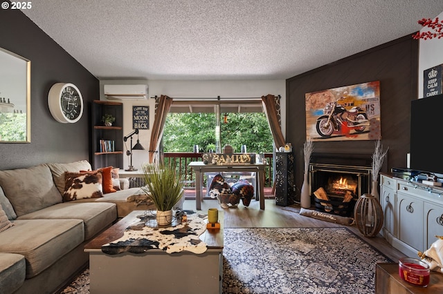 living area featuring a warm lit fireplace, wood finished floors, a wall mounted air conditioner, and a textured ceiling