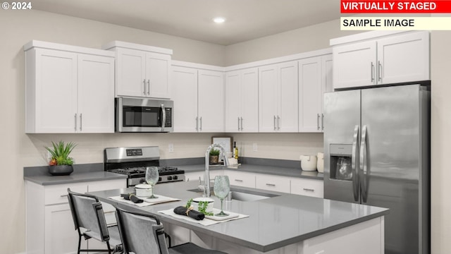 kitchen with a sink, stainless steel appliances, a breakfast bar area, and white cabinetry