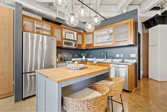 kitchen with appliances with stainless steel finishes, butcher block countertops, a sink, and open shelves