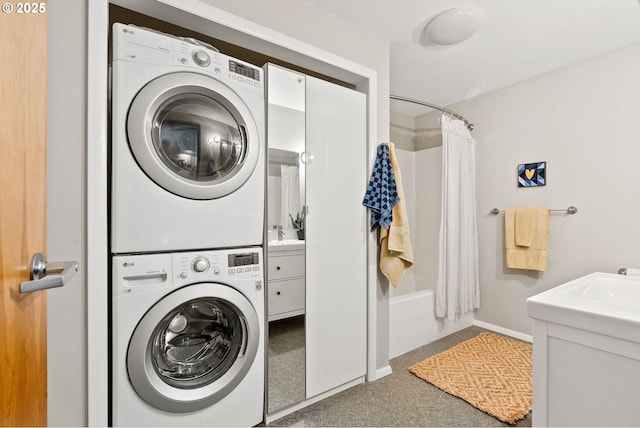 clothes washing area featuring stacked washer and dryer, baseboards, and laundry area