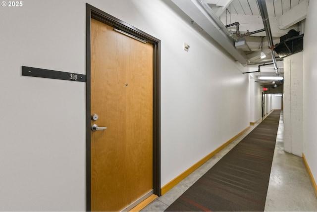 corridor with concrete floors and baseboards