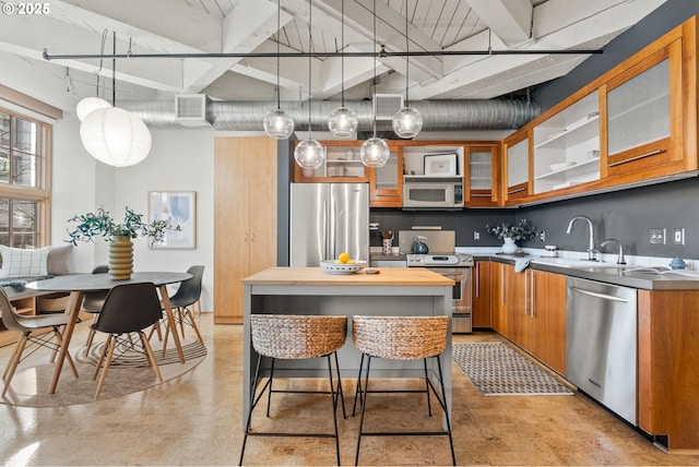 kitchen with visible vents, appliances with stainless steel finishes, brown cabinets, finished concrete floors, and a sink