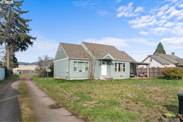 bungalow with a shingled roof, a front yard, and fence